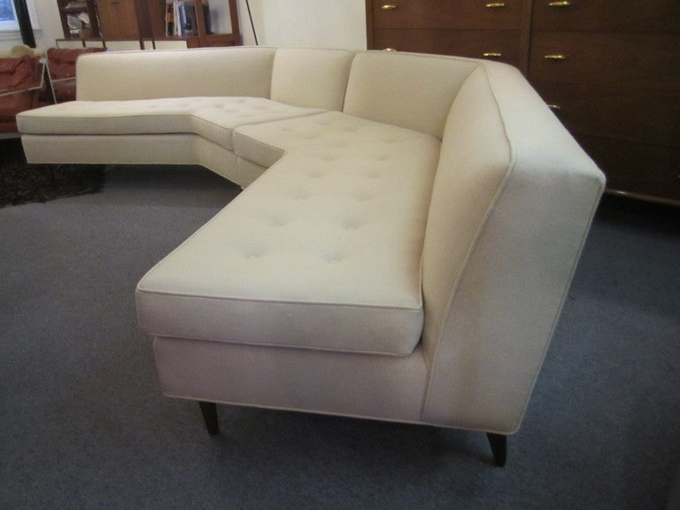 Large two piece sofa redone in cream hopsack weave fabric.  Sofa can be configured several different ways making either a deep or shallow U shape. Legs are conical and of solid walnut.  Bought from original owner and reupholstered.